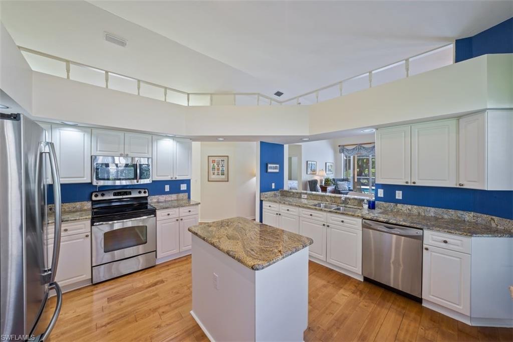 156 Napa Ridge Way Naples, FL 34119 - Photo 6 of 21 a kitchen with white cabinets and stainless steel appliances