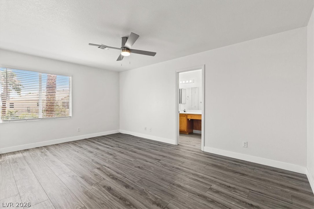 1412 Beaver Spring Street Las Vegas, NV 89128 - Photo 11 of 20 A spacious room featuring wide-plank flooring and a contemporary ceiling fan, offering direct access to an attached bath.