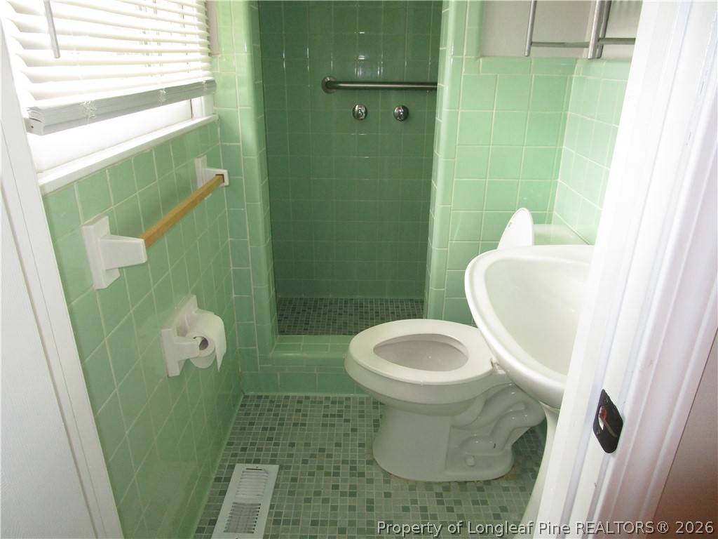 2516 Cumberland Road Fayetteville, NC 28306 - Photo 10 of 20 a white toilet sitting next to a bathroom sink and a shower