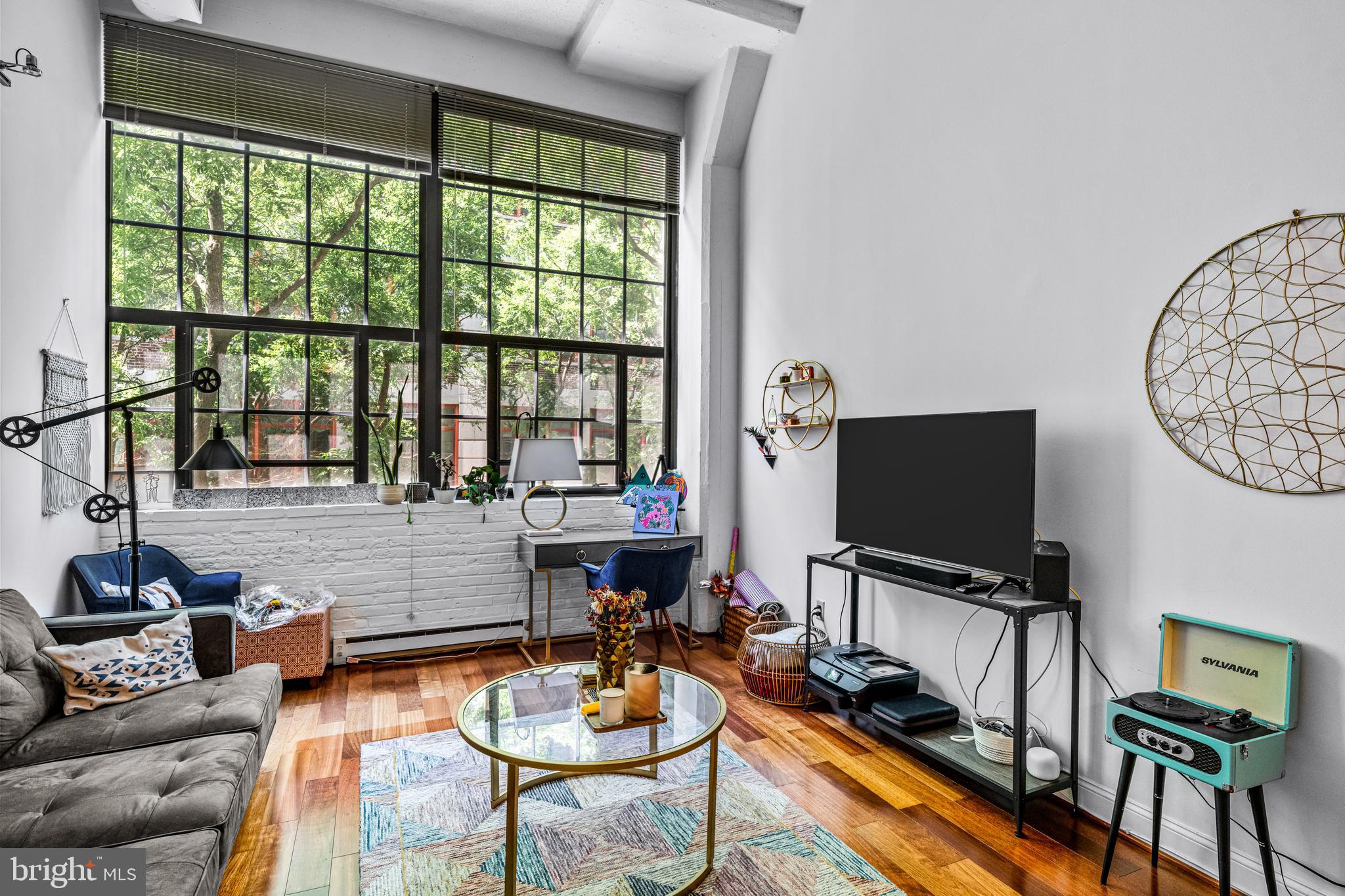 2429-41 Locust Street, Unit 219 Philadelphia, PA 19103 - Photo 15 of 28 a living room with furniture a flat screen tv and a floor to ceiling window