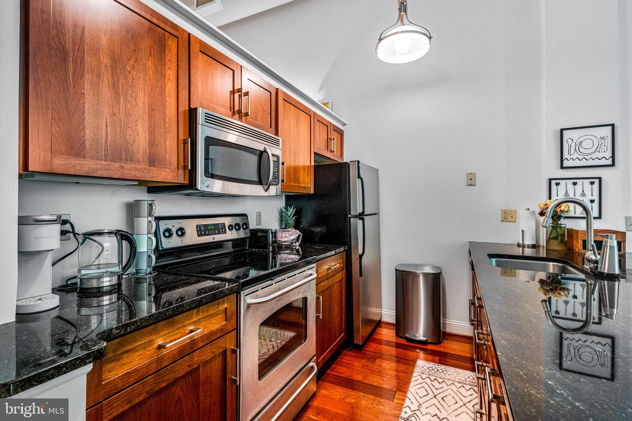 2429-41 Locust Street, Unit 219 Philadelphia, PA 19103 - Photo 10 of 28 a kitchen with stainless steel appliances a stove a refrigerator a sink a stove cabinets and a dining table