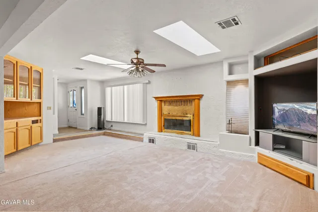 a view of an empty room with a fireplace and a window