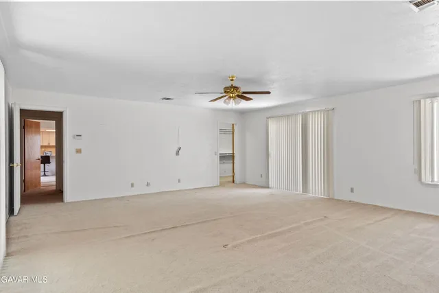 a view of an empty room with chandelier fan