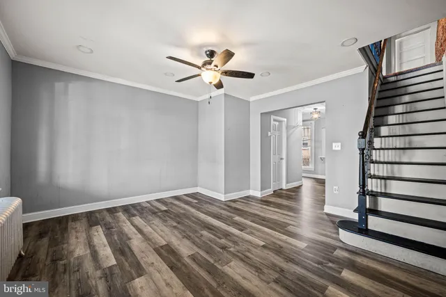 a view of an empty room with wooden floor and a ceiling fan