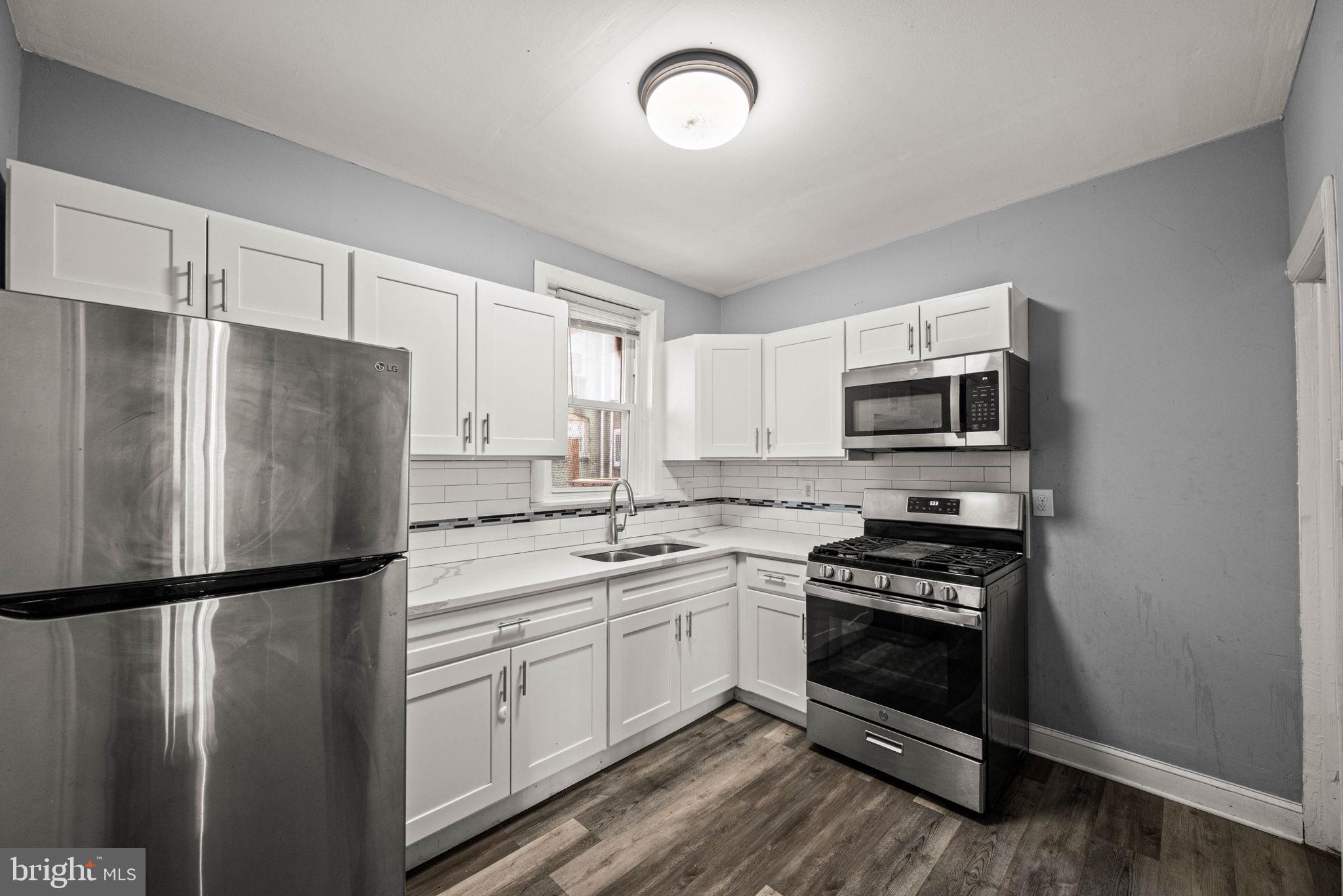 5426 Windsor Street Philadelphia, PA 19143 - Photo 8 of 22 a kitchen with stainless steel appliances a refrigerator stove and microwave