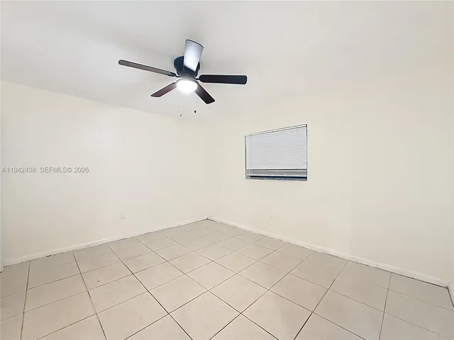 an empty room with a ceiling fan and a window