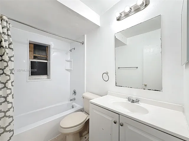 a bathroom with a toilet a sink a mirror a bathtub and vanity