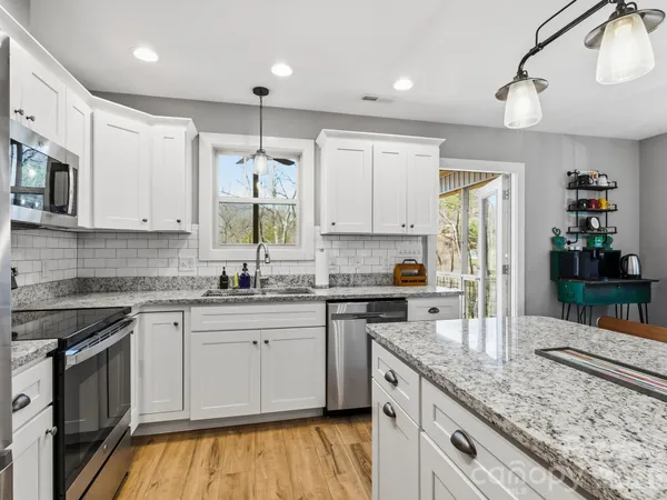 a kitchen with stainless steel appliances granite countertop a sink stove and refrigerator