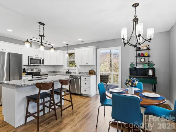 a kitchen with stainless steel appliances a dining table chairs stove and refrigerator