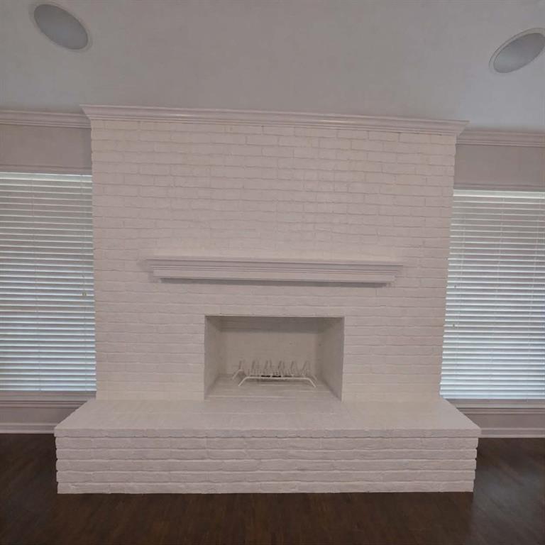 14752 Ranch Road Forney, TX 75126 - Photo 8 of 40 Expansive white-painted brick fireplace featuring a hearth and mantel, complemented by dark wood-finish flooring, crown molding, and recessed ceiling speakers- This photo was taken before family moved in