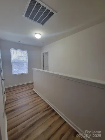 a view of empty room with wooden floor and fan