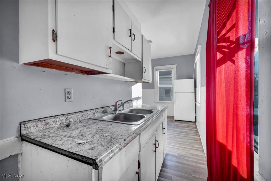 3405 Roehl Avenue Cleveland, OH 44109 - Photo 19 of 50 Kitchen with white cabinets, light countertops, freestanding refrigerator, and light wood-style floors