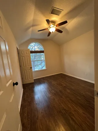 a view of a room with wooden floor ceiling fan and window