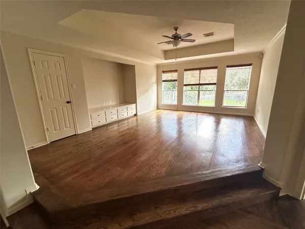 a view of empty room with wooden floor and fan