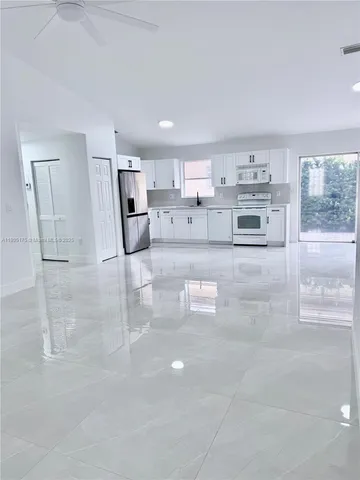 a living room with stainless steel appliances furniture and a kitchen view