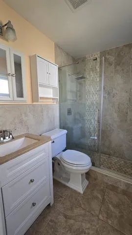 a bathroom with a granite countertop toilet a sink a mirror and shower