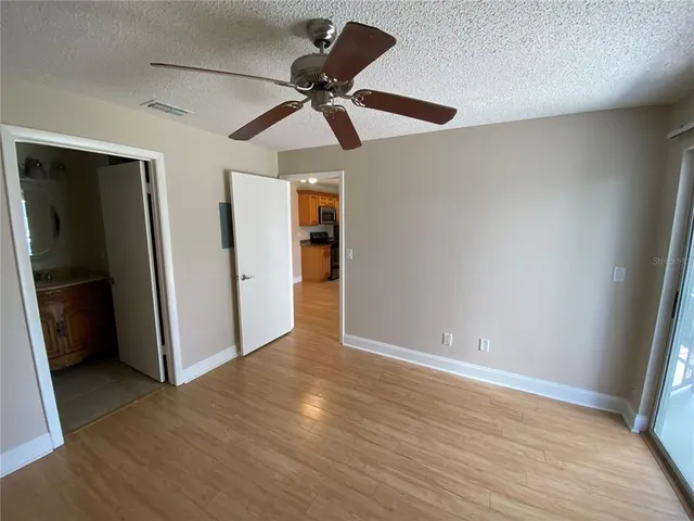 an empty room with wooden floor closet and windows