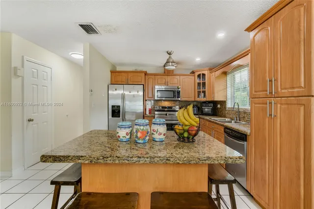 a kitchen with stainless steel appliances granite countertop sink refrigerator and cabinets