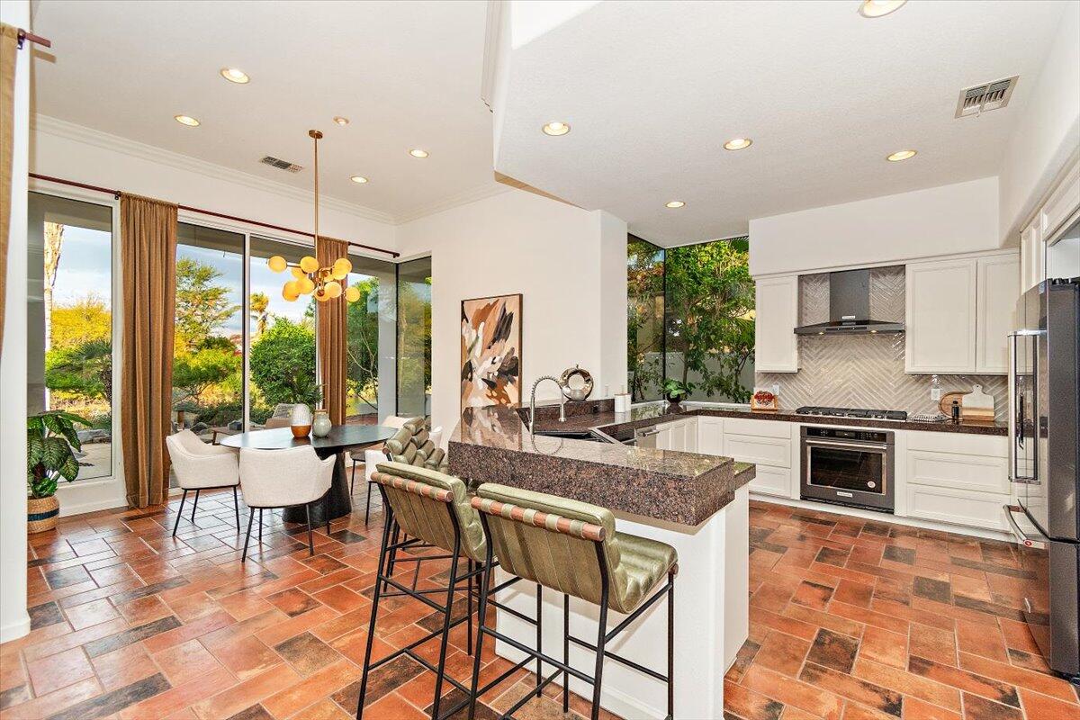 215 Loch Lomond Road Rancho Mirage, CA 92270 - Photo 10 of 57 a kitchen with stainless steel appliances granite countertop sink stove and white cabinets with wooden floor