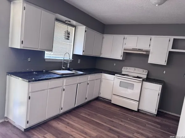 a kitchen with granite countertop white cabinets and white appliances