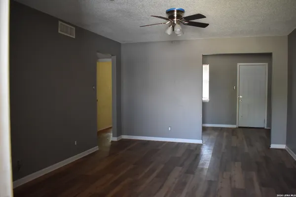 an empty room with wooden floor a ceiling fan and windows