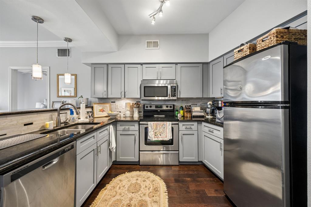 3102 Kings Road, Unit 1211 Dallas, TX 75219 - Photo 7 of 27 Well-appointed kitchen featuring light gray cabinetry, stainless steel appliances, dark countertops, a tiled backsplash, and recessed and pendant lighting
