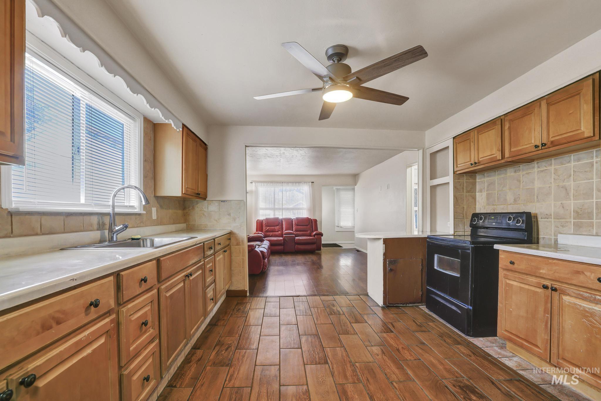 322 Jackson Street Twin Falls, ID 83301 - Photo 11 of 47 Kitchen featuring wood-finish flooring, light wood cabinetry, light countertops, and a tile backsplash
