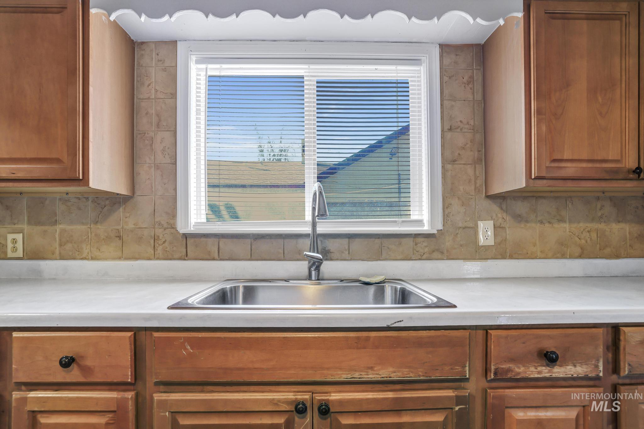 322 Jackson Street Twin Falls, ID 83301 - Photo 12 of 47 Kitchen sink area featuring a stainless steel basin, a chrome gooseneck faucet, and a tile backsplash
