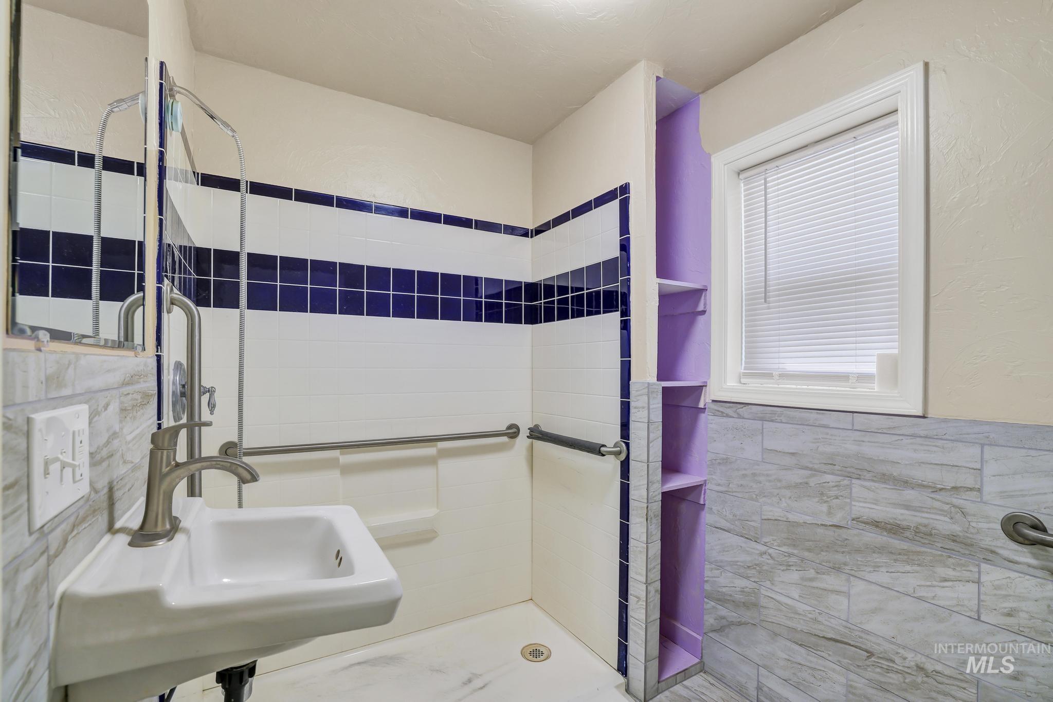 322 Jackson Street Twin Falls, ID 83301 - Photo 19 of 47 Bathroom with a wall-mounted sink, brushed nickel faucet, and a tiled shower area featuring grab bars