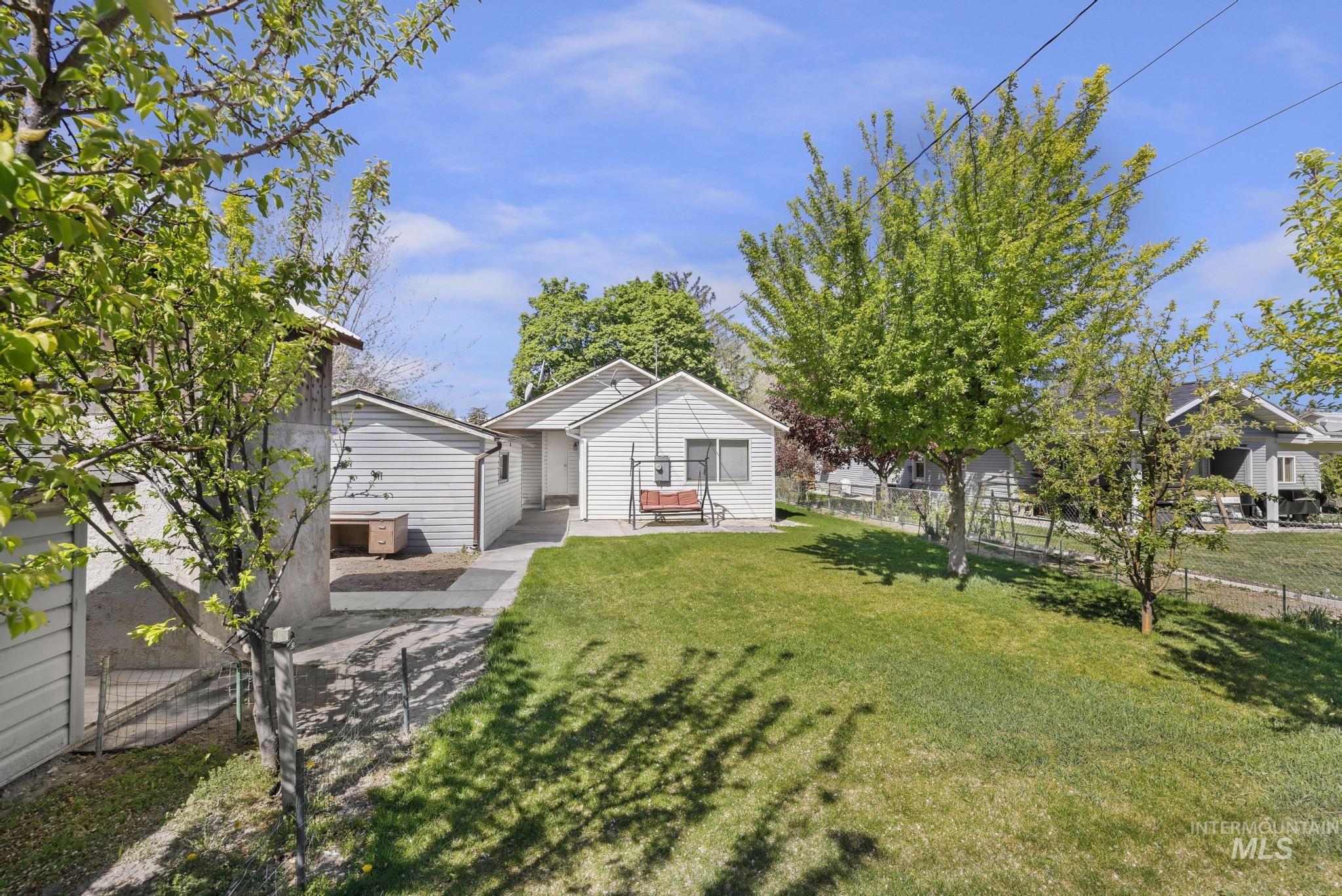 322 Jackson Street Twin Falls, ID 83301 - Photo 26 of 47 Expansive backyard featuring a lush lawn, mature trees, and a concrete pathway leading to the main residence