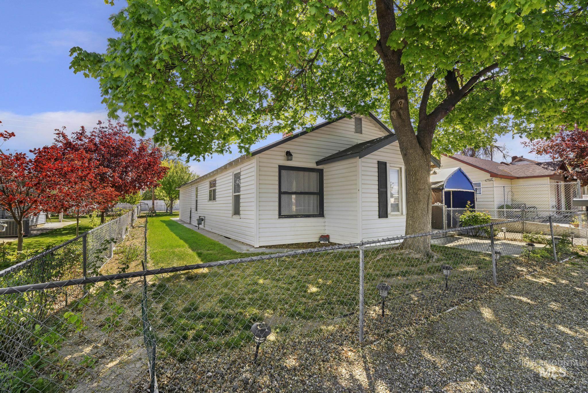 322 Jackson Street Twin Falls, ID 83301 - Photo 35 of 47 White horizontal siding exterior with black window trim and a shaded front yard featuring mature trees