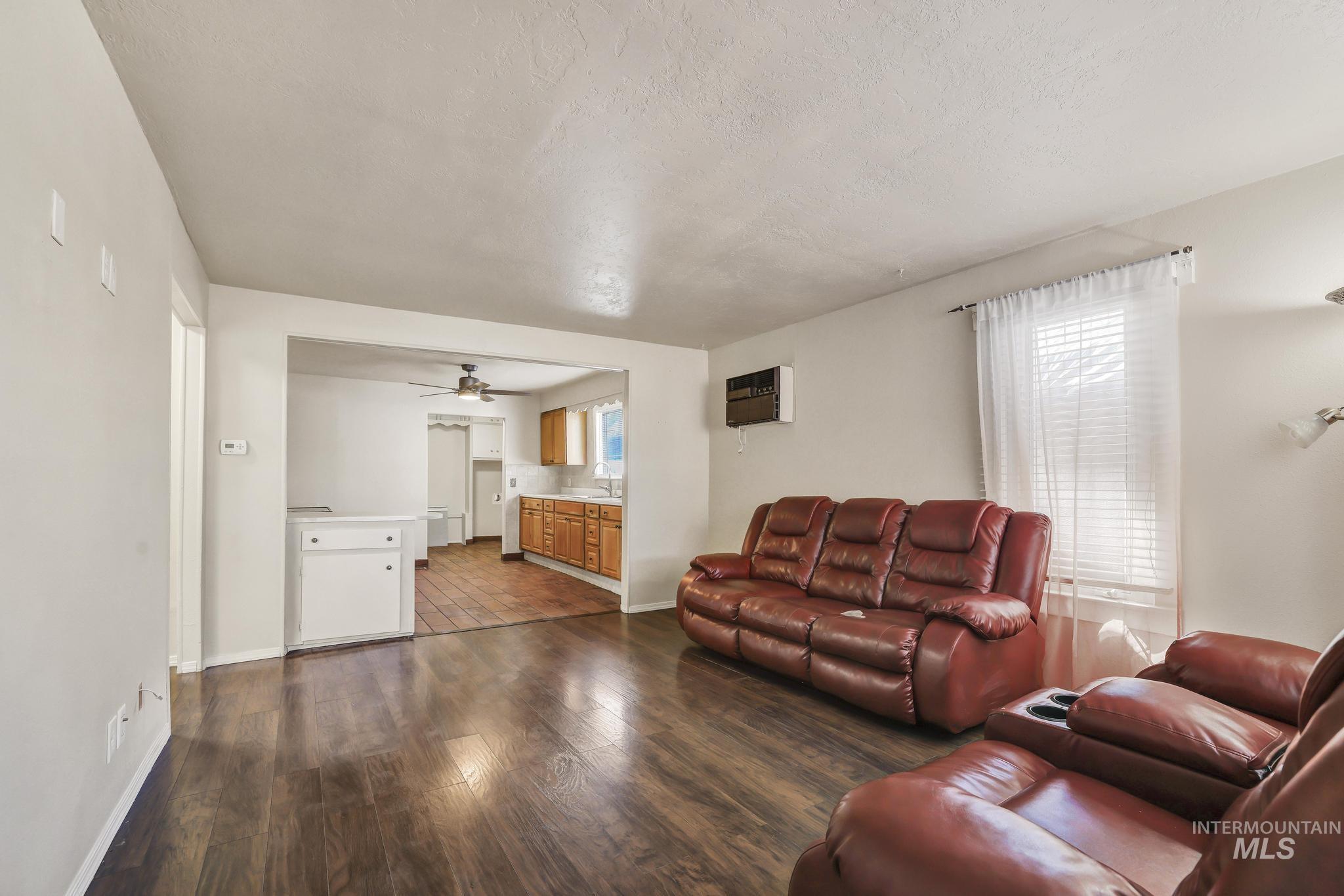 322 Jackson Street Twin Falls, ID 83301 - Photo 5 of 47 Living area featuring wood-finish flooring, light neutral wall tones, and an opening to the kitchen