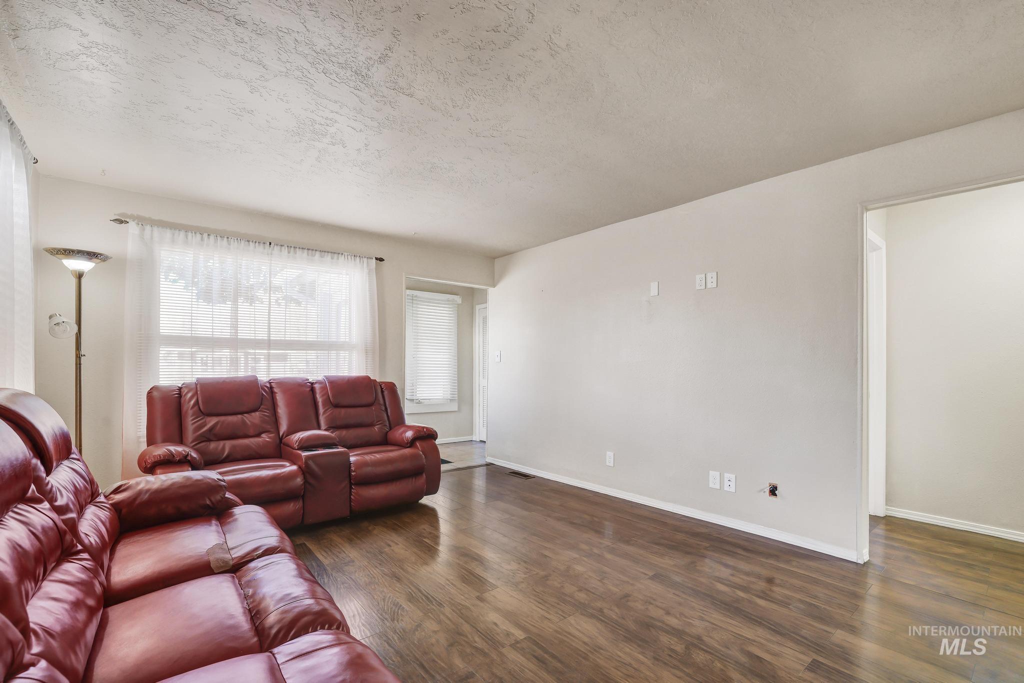 322 Jackson Street Twin Falls, ID 83301 - Photo 7 of 47 Spacious interior featuring wood-finish flooring, white walls, and a large window with sheer curtains