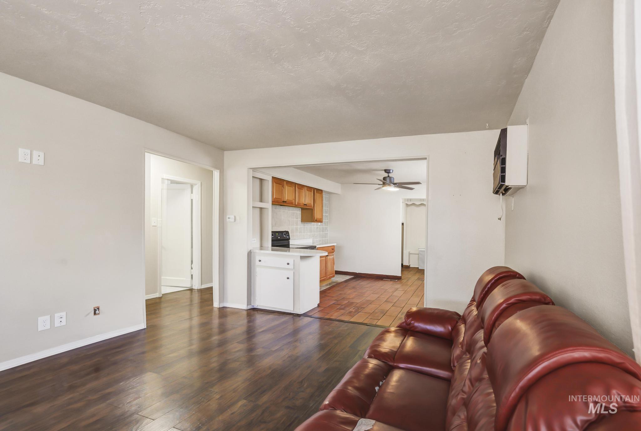 322 Jackson Street Twin Falls, ID 83301 - Photo 8 of 47 Living area featuring wood-finish flooring, a pass-through to the kitchen, and a wall-mounted air conditioning unit