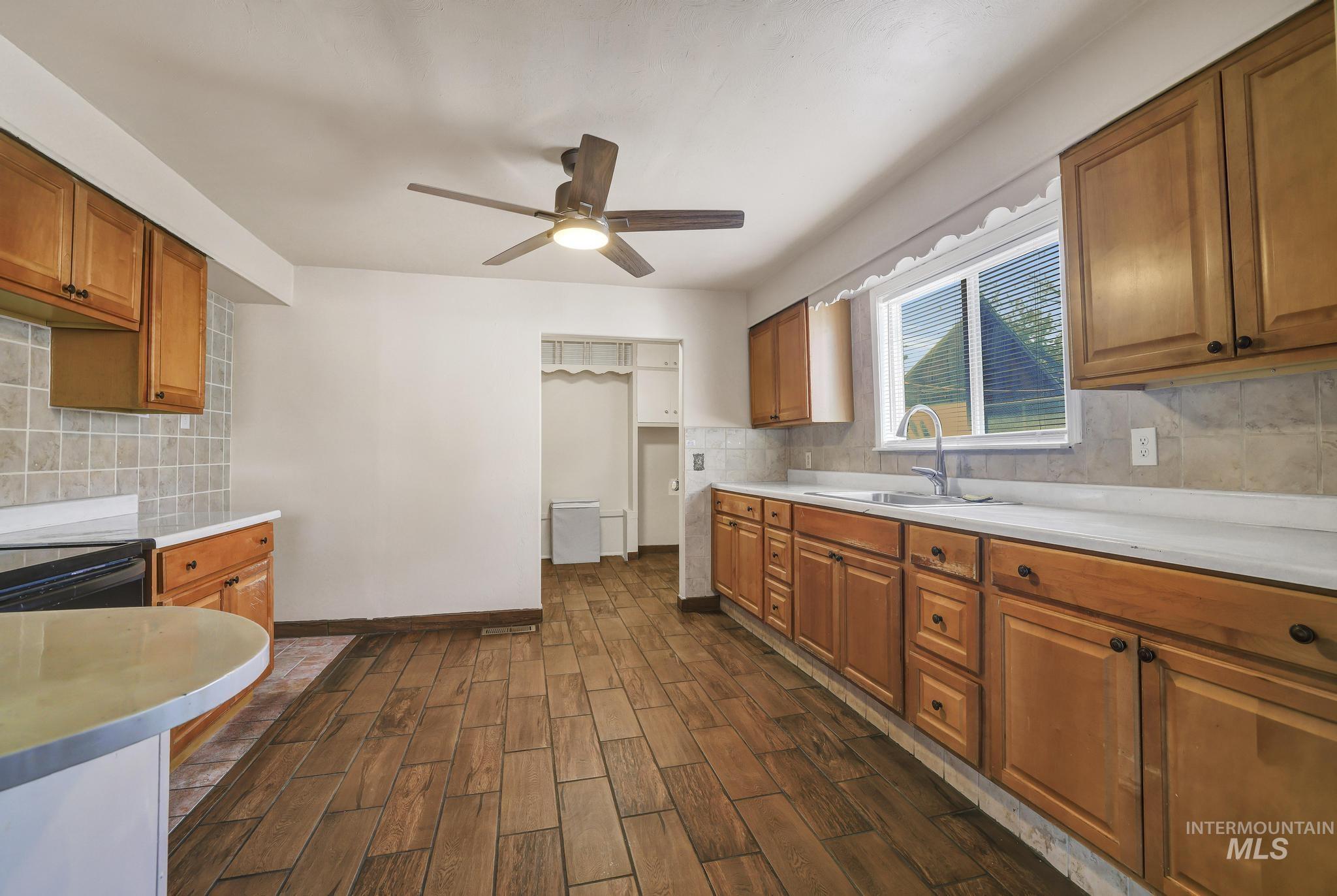 322 Jackson Street Twin Falls, ID 83301 - Photo 9 of 47 Kitchen featuring wood-finish flooring, natural wood cabinetry, light-toned countertops, and a tiled backsplash