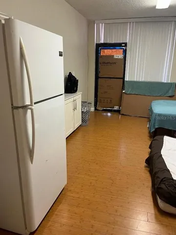 a view of room with refrigerator and wooden floor