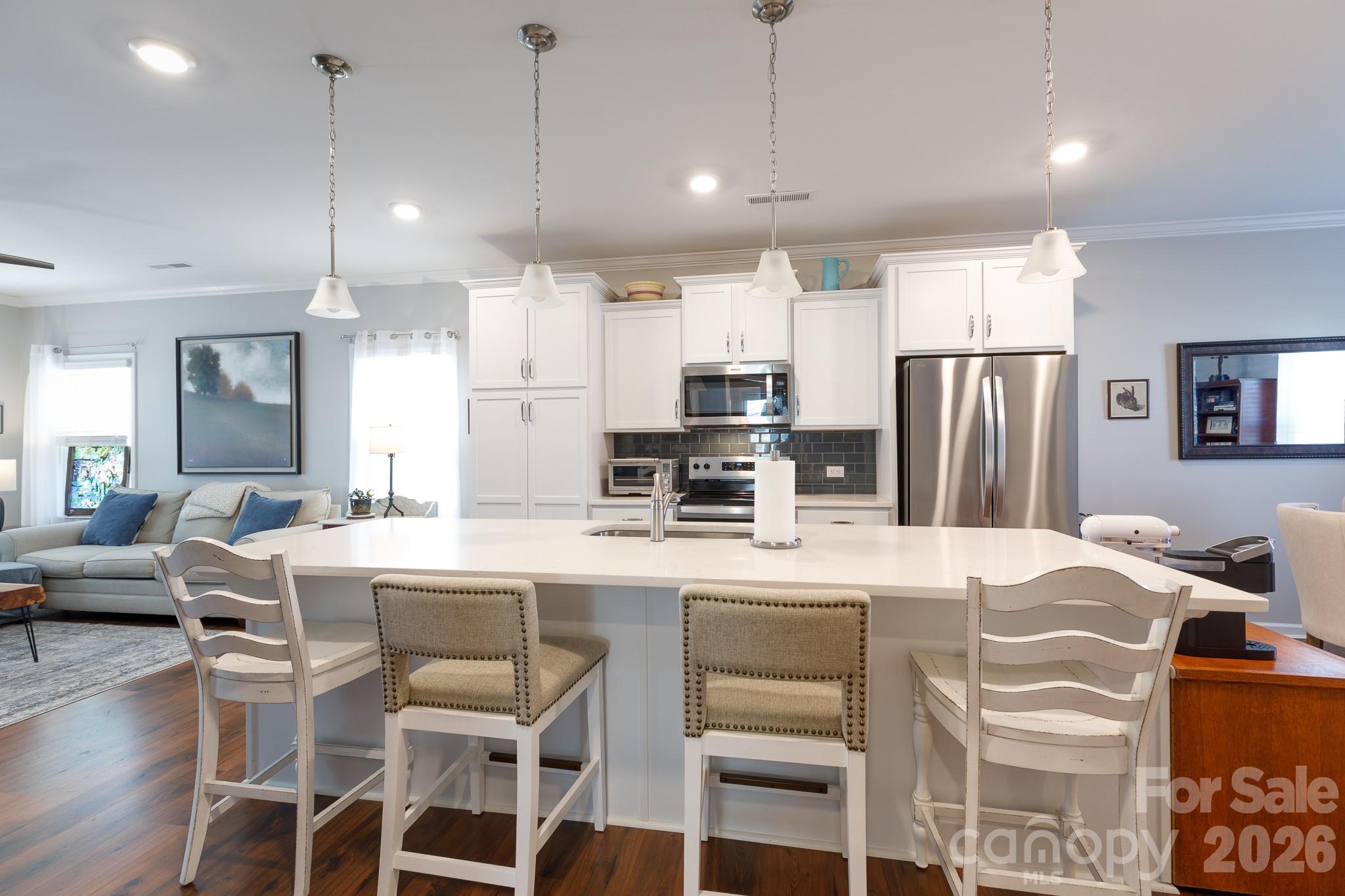 40308 Crooked Stick Lane Lancaster, SC 29720 - Photo 10 of 46 a kitchen with kitchen island a refrigerator a stove a dining table and chairs with wooden floor