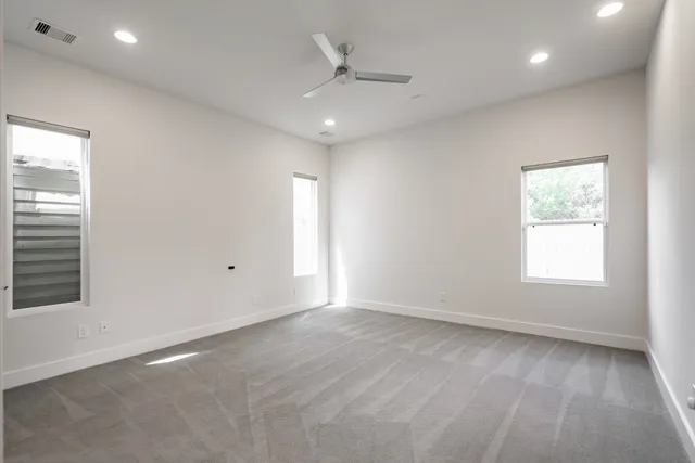 an empty room with a window and a ceiling fan