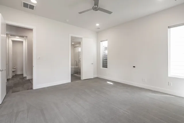 an empty room with a fan & a window