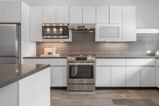 a kitchen with stainless steel appliances granite countertop a stove a microwave and a refrigerator