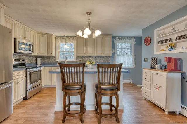 a kitchen with stainless steel appliances kitchen island granite countertop a table chairs sink and cabinets