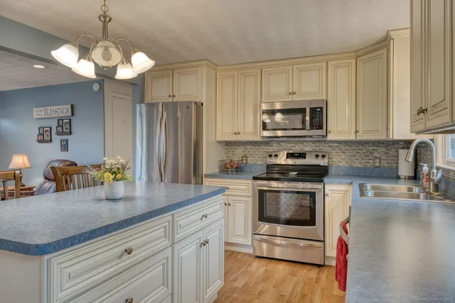 a kitchen with stainless steel appliances granite countertop a sink a stove a microwave a refrigerator a counter space and cabinets