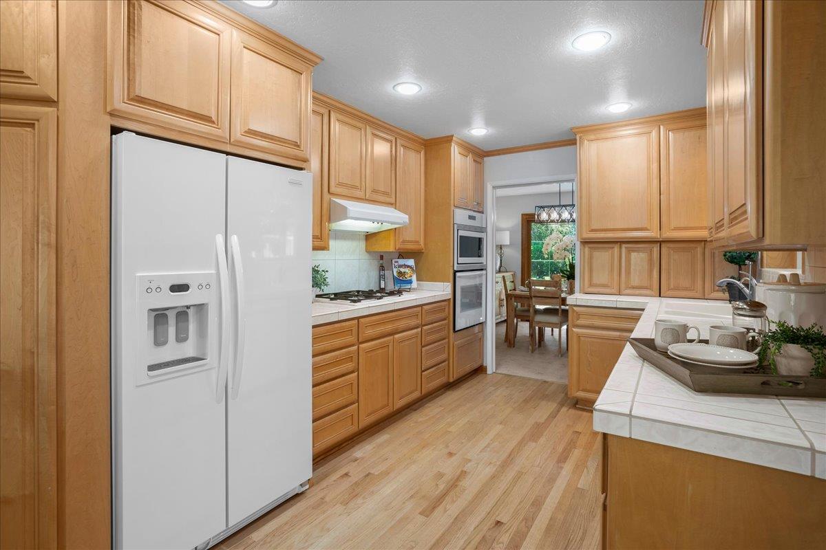 1816 Dry Creek Road San Jose, CA 95124 - Photo 14 of 37 a kitchen with stainless steel appliances kitchen island granite countertop a refrigerator a sink dishwasher a stove and white cabinets with wooden floor