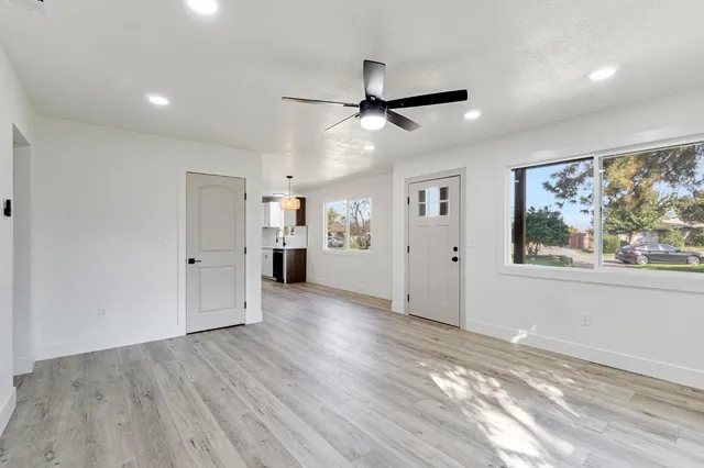 a kitchen with stainless steel appliances a stove top oven a sink a refrigerator and white cabinets with wooden floor