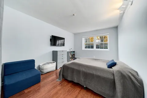 a bedroom with a bed a couch and a flat tv screen on a dresser