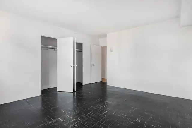 a view of an empty room with wooden floor and closet