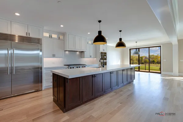 a kitchen with kitchen island granite countertop wooden floors stainless steel appliances and sink