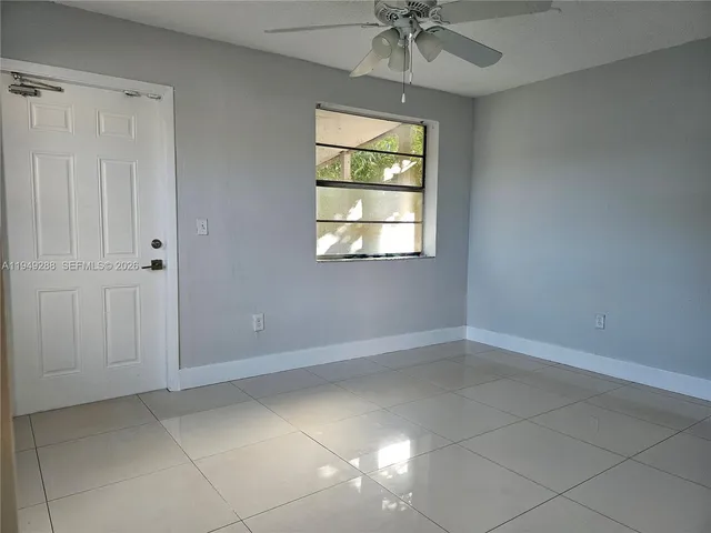 en empty room with windows and chandelier fan
