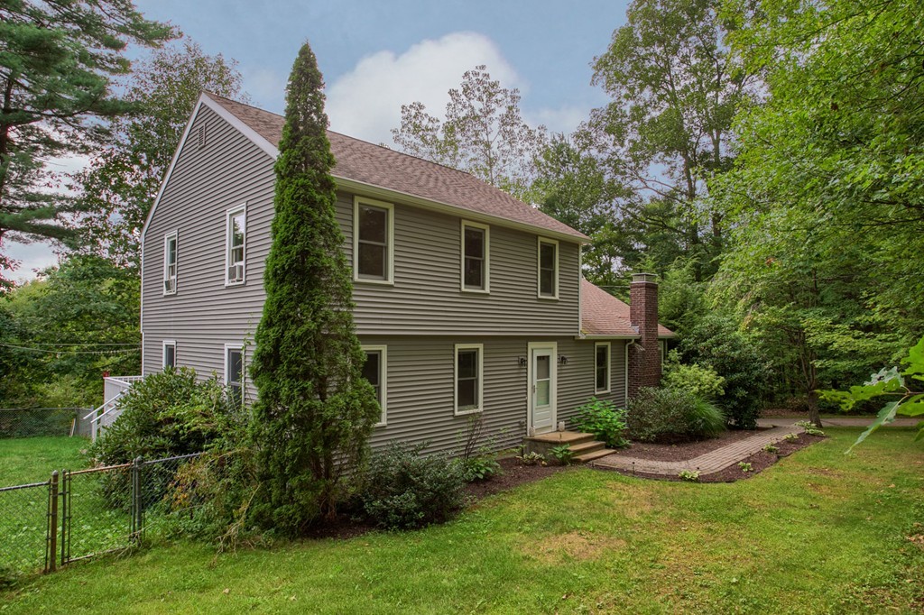 a view of a house with a yard and a large tree