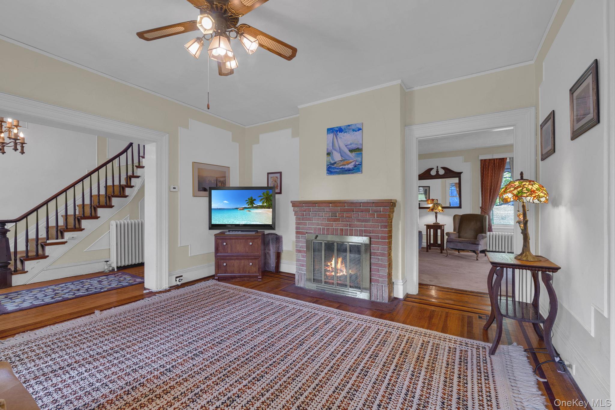 470 Little Britain Road Newburgh, NY 12550 - Photo 18 of 45 Living room featuring wood finished floors, crown molding, radiator, a fireplace, and stairs